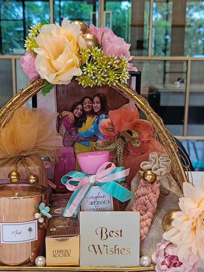 The golden wire basket filled with thoughtful gifts, including a personalized photo frame, a scented candle, and other small, beautifully packaged items.