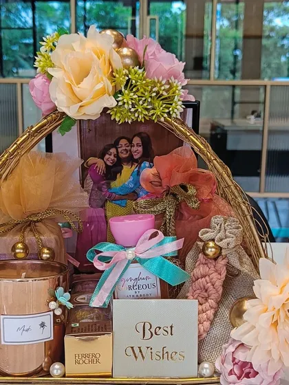 A top-down view of the golden wire basket, showing the rich assortment of gifts and the beautiful floral arrangement on top.