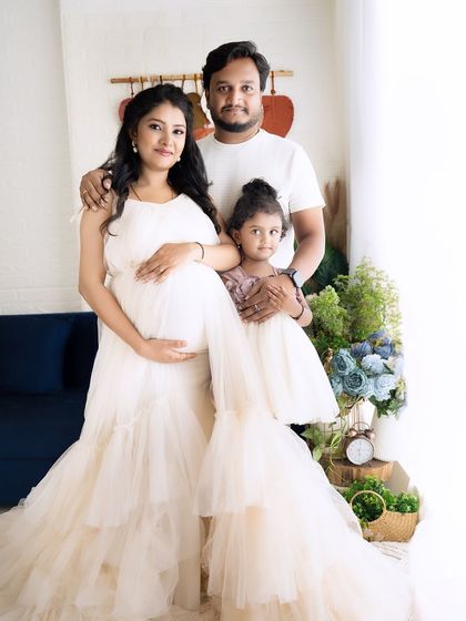 A beautiful family portrait with the parents and their daughter, all dressed in coordinating cream outfits, creating a harmonious and loving image.