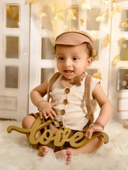This little boy holds a "love" sign, completing the charming look of his boho-chic photoshoot.