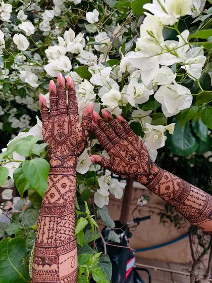 The beauty of fresh henna against a natural backdrop. This full-arm design showcases a dense pattern with geometric and floral elements, demonstrating the crisp line work I strive for in every piece.