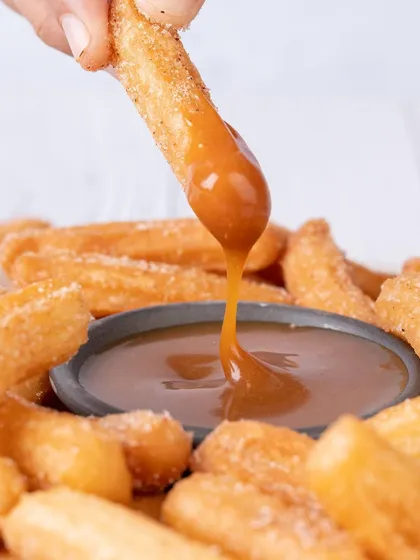 There's nothing more tempting than a perfect dip. This shot for It's Minidonuts focuses on the luscious caramel texture and the satisfying action, creating a mouth-watering image that highlights the quality of the dessert.