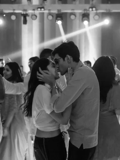 Aania and Aasim find each other on a crowded dance floor. This black and white photo captures their intimate kiss, a quiet moment of connection amidst the party's energy.