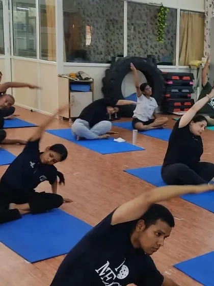 Students practicing a seated side bend. This pose helps to stretch the sides of the body, improve spinal flexibility, and release tension in the shoulders.
