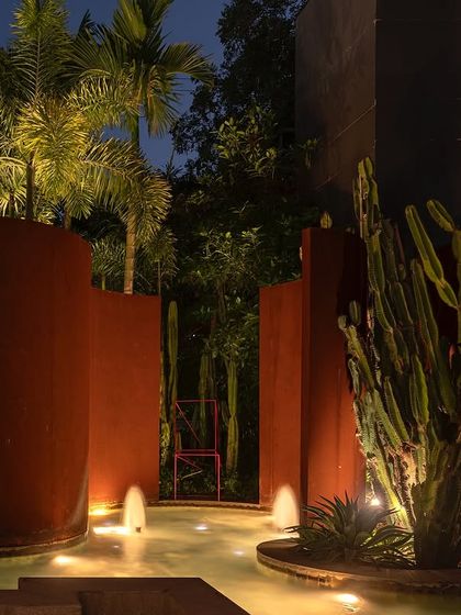The KEUS landscape at night, with the Corten steel walls and cacti dramatically lit. The space is transformed into a vibrant area for events, showcasing the versatility of the design.