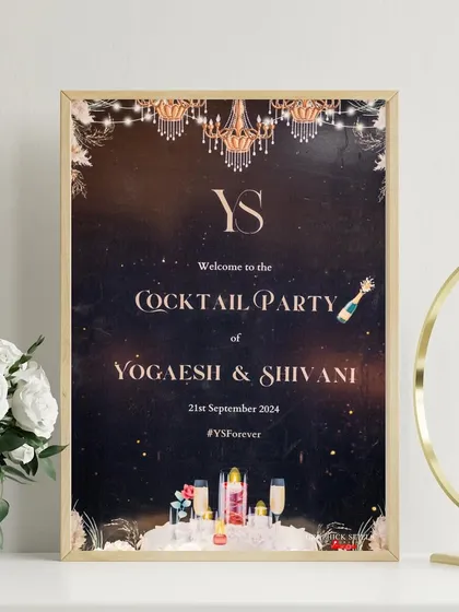 Here is the cocktail party signage displayed in a beautiful gold frame. The design elements, from the custom 'YS' monogram to the illustrated cocktail bottles, create an inviting and festive welcome for guests.