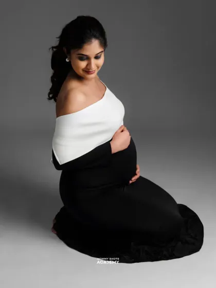 A graceful kneeling pose in a black gown, demonstrating how to create elegant lines and highlight the bump.