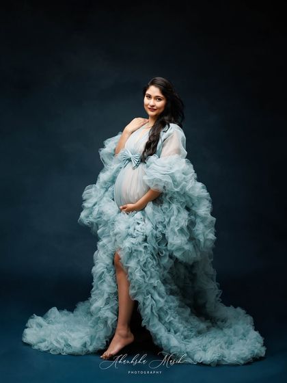 The full silhouette of this incredible blue ruffled gown is on display, creating a portrait that is both majestic and graceful.