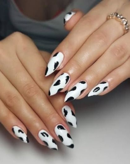 A fun and trendy cow print design on long, stiletto-shaped nails. This black and white pattern is always a stylish choice.