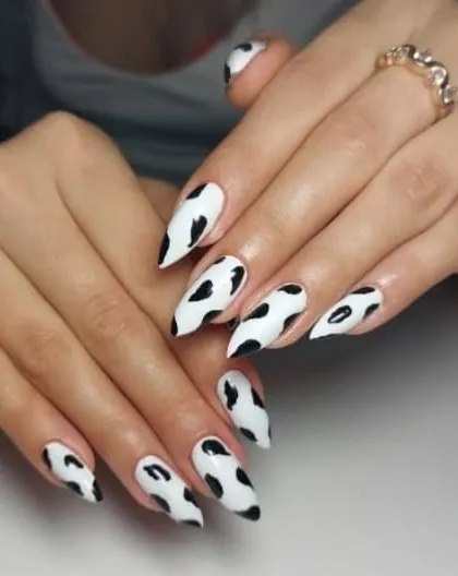A fun and trendy cow print design on long, stiletto-shaped nails. This black and white pattern is always a stylish choice.