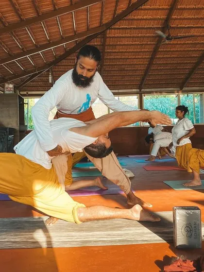 This is a duplicate of image 116. A student receives an adjustment in a supported backbend, showing our commitment to safe and effective teaching.