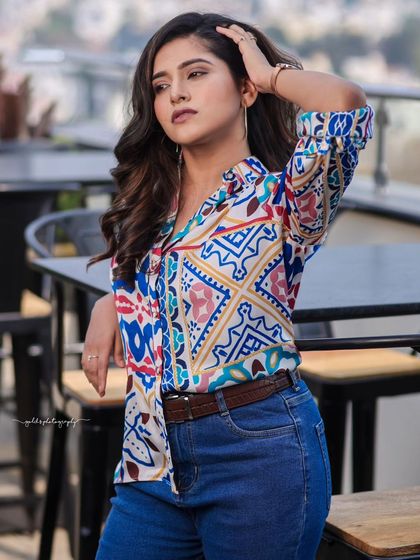 A lifestyle fashion shoot for an actress, featuring a colorful printed shirt and blue jeans. Shot in a modern cafe, these images have a bright, energetic, and youthful feel, perfect for a commercial or social media campaign.