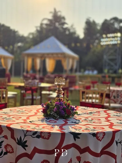 A closer look at the tablescape for the Sufi Sangeet, showing the custom linens, floral centerpiece, and the grand cabanas in the background.