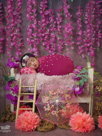 This little girl looks like a flower herself, sleeping on a bed surrounded by pink and purple blossoms. The floral theme is always a beautiful choice for a newborn baby girl's photoshoot.