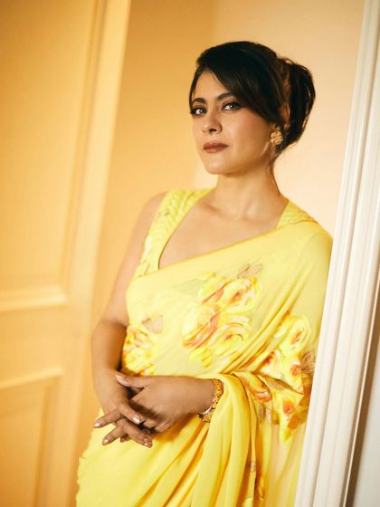 A close-up portrait showcasing the soft texture and bright hue of the yellow saree, complemented by simple gold earrings.