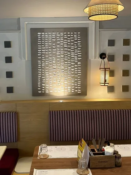 A wider view of the installation, showing how the different artworks and decorative elements create a cohesive and richly textured wall.