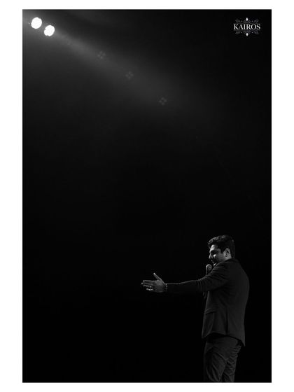An artistic, minimalist shot of a performer on a dark stage, using negative space and a single spotlight to create a powerful and dramatic image.
