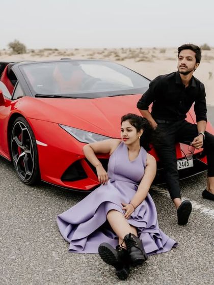 A stylish and confident pose with the couple and the red Lamborghini on the desert road.
