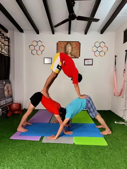 A pyramid of downward facing dogs. This is a fun acro yoga challenge for groups that builds upper body strength and creates a strong foundation together.