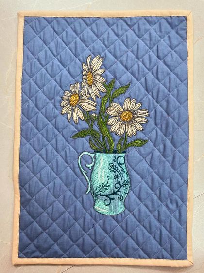 A lovely placemat with an embroidered vase of daisies, finished with diamond crosshatch quilting.