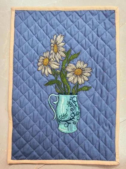 A lovely placemat with an embroidered vase of daisies, finished with diamond crosshatch quilting.