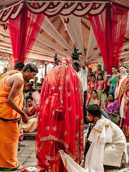 A wide shot of a traditional South Indian wedding ceremony in progress, with the bride covered by a veil before a key ritual.