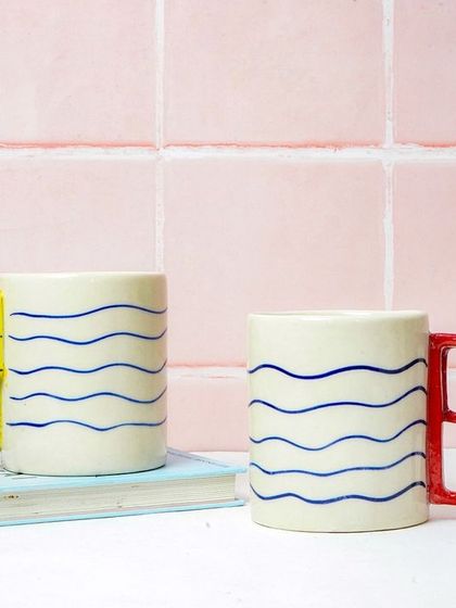 Two mugs styled with a book, creating a cozy, 'reading nook' atmosphere. This helps customers imagine using the products in their daily lives.