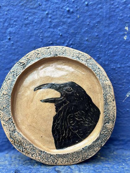 A hand-built stoneware plate featuring a sgraffito crow. I am drawn to the character and intelligence of crows, and they often appear in my work as symbols of the urban wildlife of Mumbai.