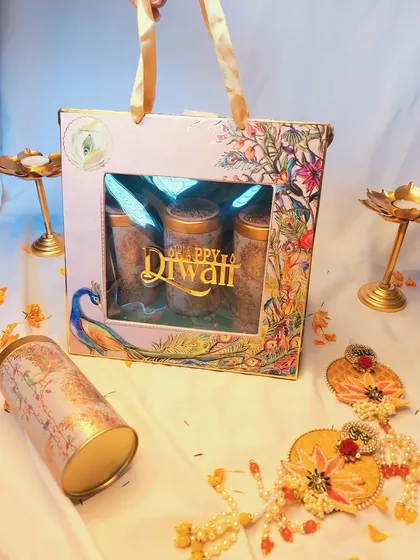 This peacock-themed Diwali gift bag is both beautiful and practical. It comes with three printed tins filled with cookies, almonds, and flavored makhana, perfect for easy gifting.