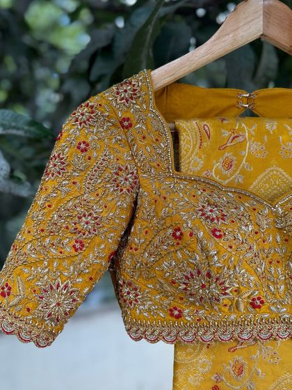 A close-up of the sweetheart neckline and detailed sleeve work on the mustard yellow bridal blouse. The combination of zari, threadwork, and scalloped edging adds layers of texture and elegance.