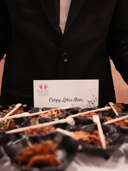 Service is just as important as the food. Here, my professional staff presents crispy lotus stem appetizers, showcasing our commitment to impeccable, white-glove service at every event.
