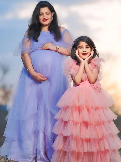 A fairytale moment captured with our mom and daughter gowns. The mother is wearing a lavender net gown, while her daughter complements her in a pink layered tulle dress.