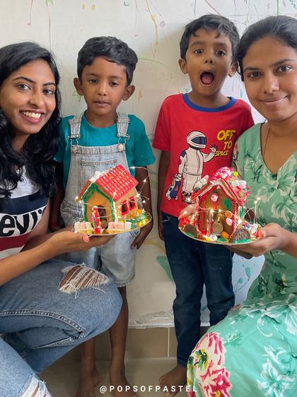 A mother and her two sons proudly display the gingerbread houses they decorated together at our festive Christmas workshop.