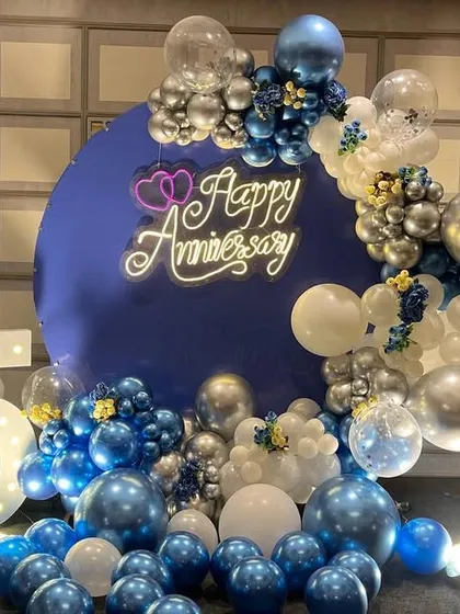 A closer view of the 25th anniversary decoration. The combination of chrome blue and silver balloons with the neon sign creates a festive and elegant atmosphere for the celebration.