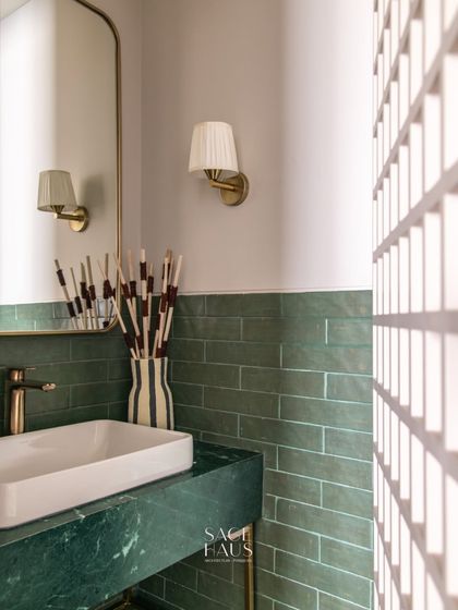 In this powder room, I paired a rich green marble vanity with matching subway tiles. The pleated wall sconce and arched mirror soften the clean lines, creating a space that feels both modern and timeless.