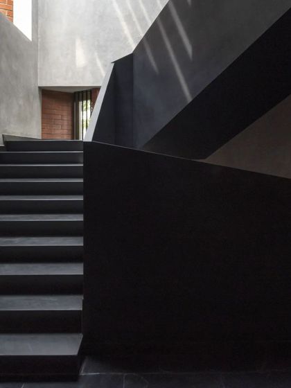 The angular forms of the Brick House staircase create a dramatic play of light and shadow, highlighting the texture of the lime plaster walls.