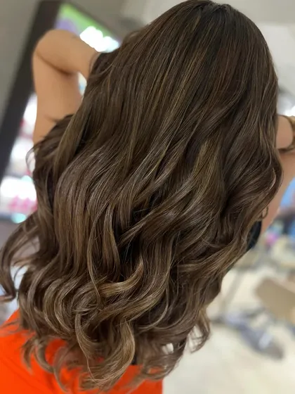A gorgeous caramel and beige highlight blend that looks stunning on long hair. The long layered haircut adds volume, and the soft waves make the color pop.