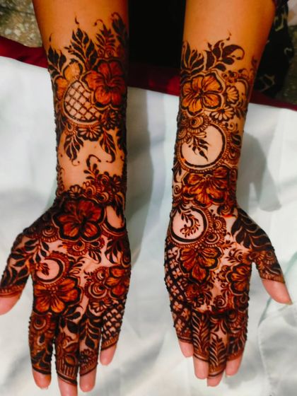 The hibiscus flower design after the henna paste has started to dry and darken, beginning the process of leaving a beautiful stain.