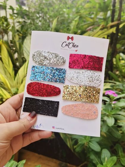 Holding up a full set of our glitter barrettes. These are perfect for parties or any time you want to add a bit of glam to your look.