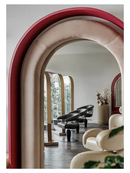 Looking through a series of layered, upholstered arches reveals the styling stations, creating a sense of depth and architectural interest.
