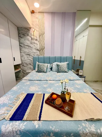 A tranquil bedroom design featuring a soothing blue and white color palette. The space includes a custom upholstered headboard, textured wall panels, and coordinated furnishings to create a complete, restful atmosphere.