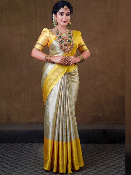 This silver and yellow silk saree creates a unique and elegant look. The draping is done to show off the beautiful contrast border and the richness of the silk.