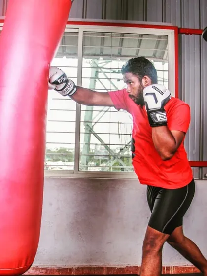 The heavy bag is an essential tool for developing power and technique. Here, a trainee practices a straight right hand, focusing on full extension and hip rotation to generate maximum force. This is fundamental to our boxing for fitness program.