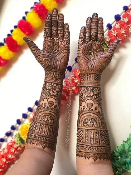 A full-arm mehendi design with a festive background. The patterns are traditional and dense, perfect for a wedding or major celebration.