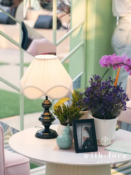A tabletop detail from the baby shower, with a vintage-style lamp and small floral arrangements.