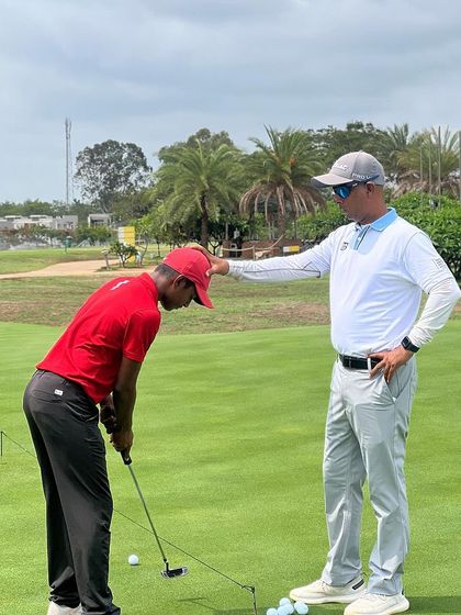 A coach gives a putting lesson on the practice green. Mastering the short game is a huge focus in our training programs.