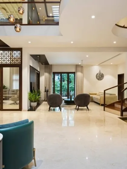 A wide-angle view of a grand, open-plan home. You can see the multiple seating areas, the sweeping staircase, and the connection to the upper floor, all working together to create a sense of spaciousness and luxury.