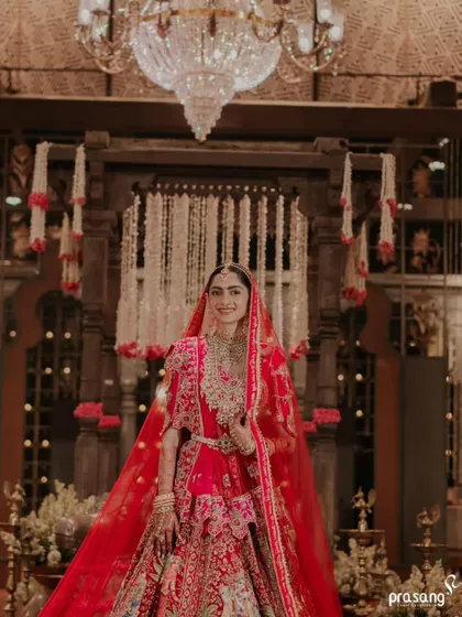 The bride, framed by an ornate wooden structure and a crystal chandelier. I combine different decor elements to create layers of texture and luxury, resulting in stunning photographic moments like this.