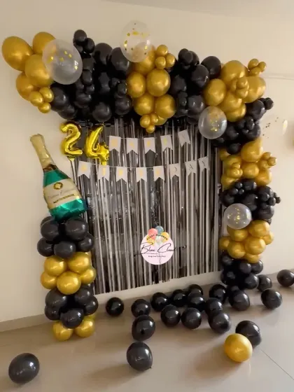 A sophisticated black and gold balloon arch with a shimmer curtain for a 24th birthday celebration.