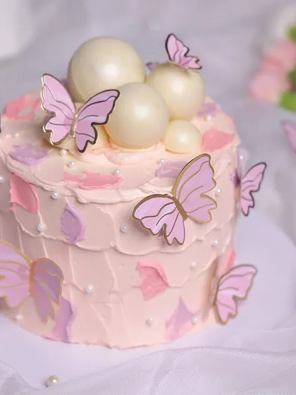Our Pink Butterfly Cake is a vision of delicate beauty, with textured pink frosting, pearl-like spheres, and gold-trimmed butterflies.
